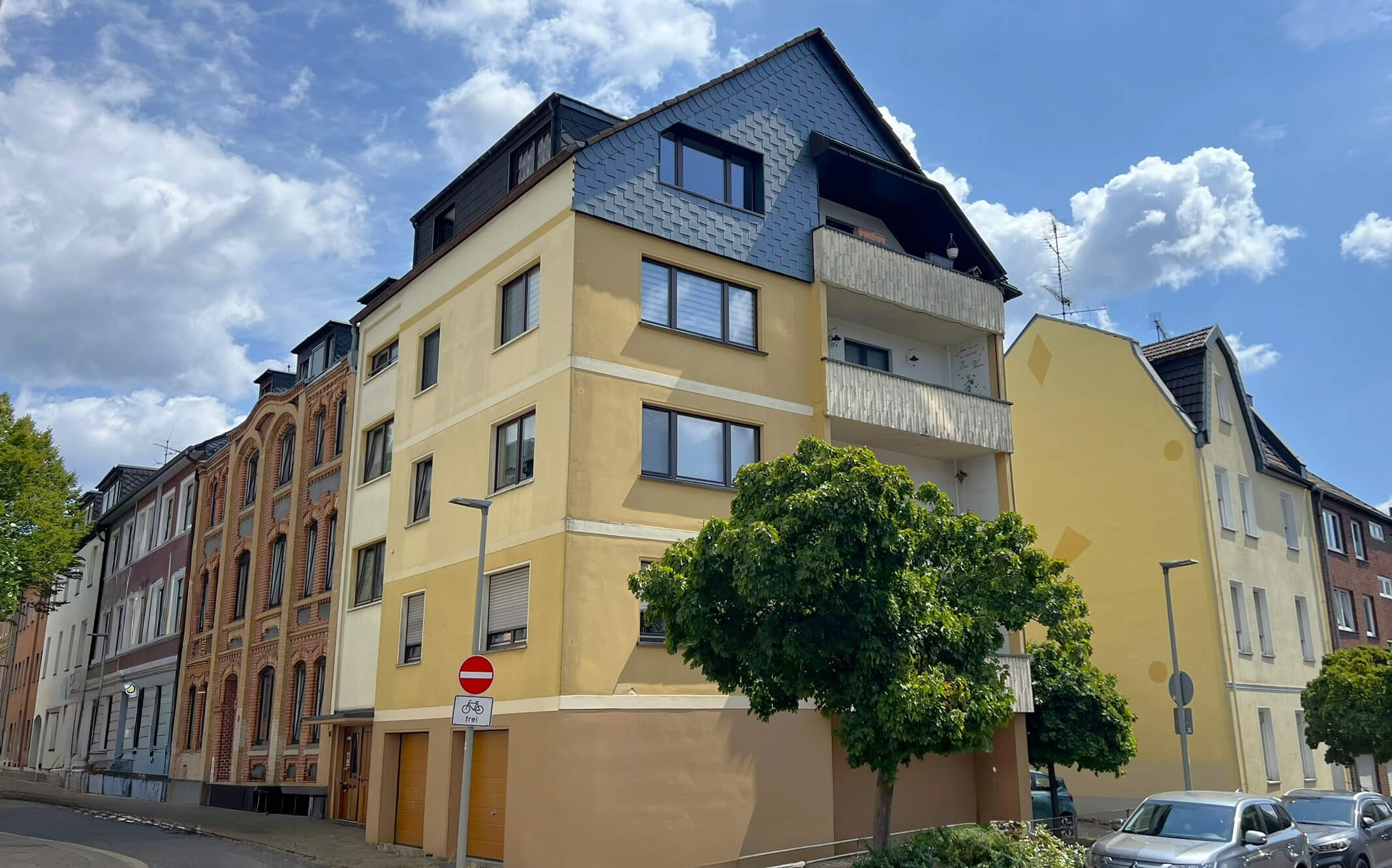 Außenansicht einer 4-stöckigen Wohnungsimmobilie mit gelber Fassade